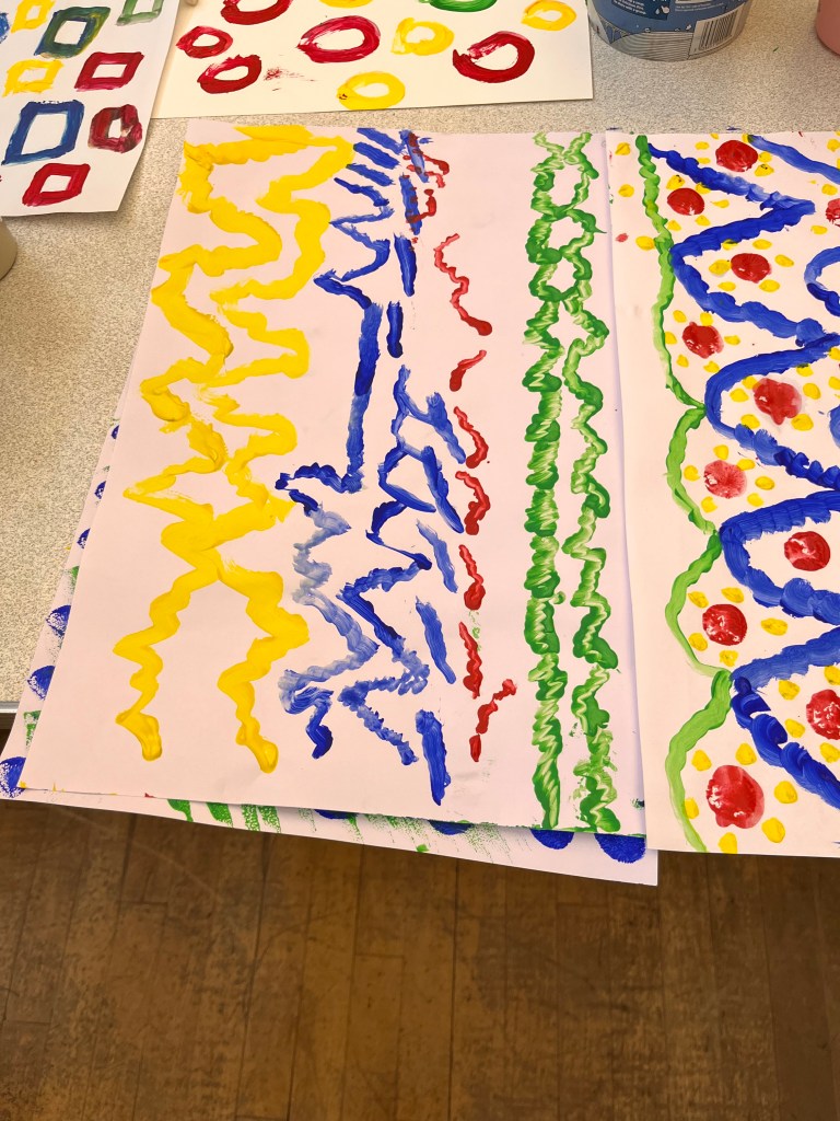 photo of artwork. one is a rainbow of squares, next to it is a rainbow of circles. Below is lines of different zigzags in green, red, blue and yellow. Beside it is some painted arches in green and blue with red and yellow dots inside them.  