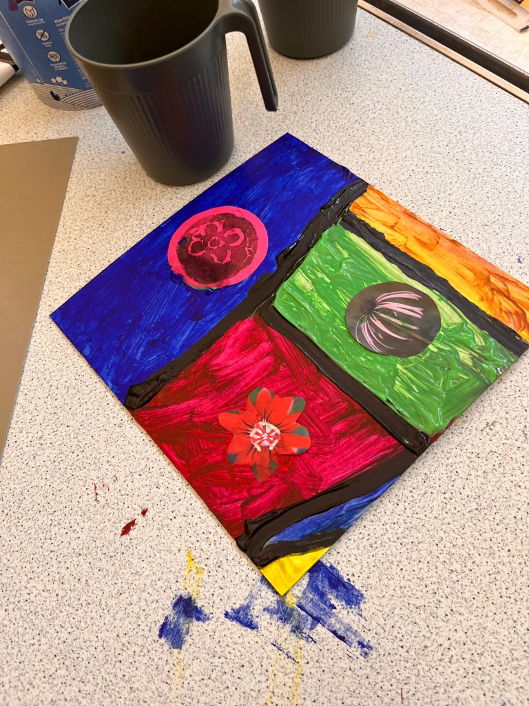 One of the panels of the church collage. Different sections ares painted different colours on the top its blue with a pink orb. In the middle its red with a red flower. Next is a green section with  a grey sphere with white lines and then a yellow bit.