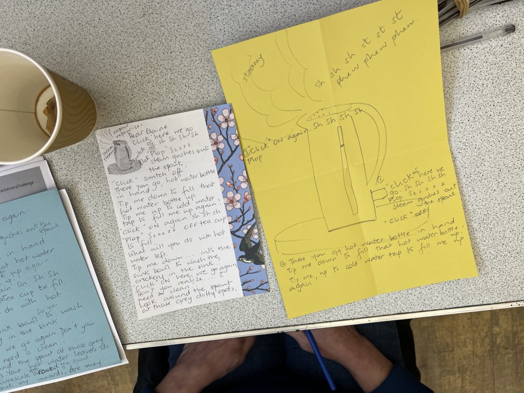 picture of members work. there are two pieces of paper on a table. On the yellow sheet there is a sketch of  kettle with the words of the sound effects it makes. beside it is a smaller white piece of paper which is a letter from the kettle.