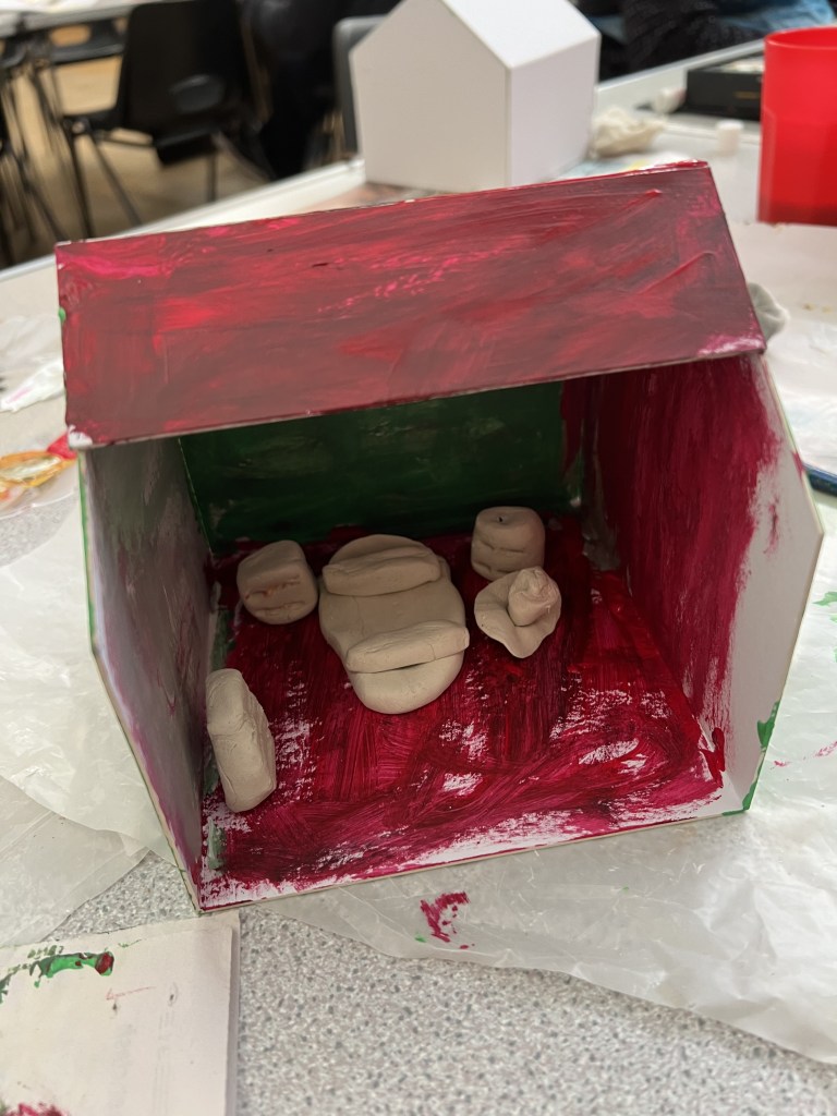 model house painted a brownish red. There are various white clay furnishings such as a bed.