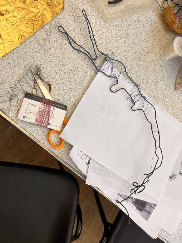 image of a wirework crocodile or aligator. There is thread wrapped around it.