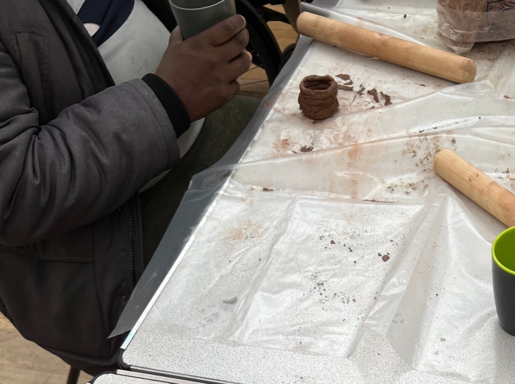 photo of paricipant drinking a cup of tea. slightly off to the center is their pot and a rolling pin.