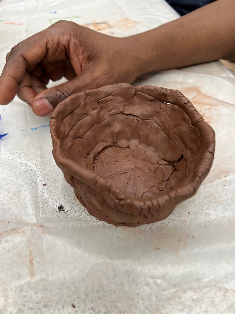 image of a tall pot with a base and is uneven around the sides.