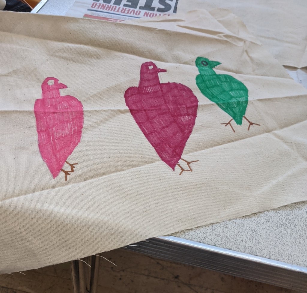 three birds drawn and coloured on Eritrean fabric. the birds are pink, magenta and green.