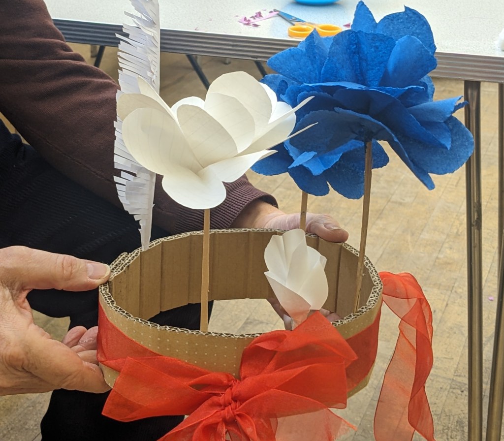 Carboard hat with a white and blue tissue paper flower attached.