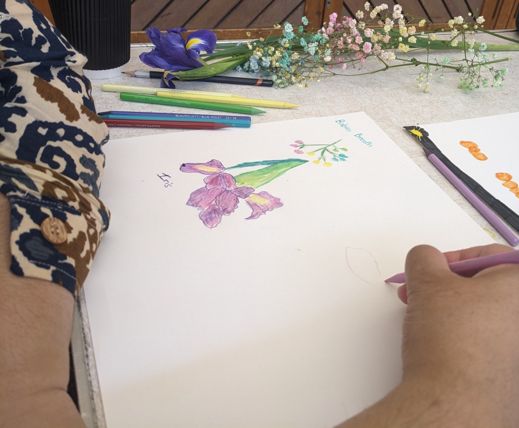 Someone drawing an Iris. Flowers like bluebells are placed on side of the drawing.
