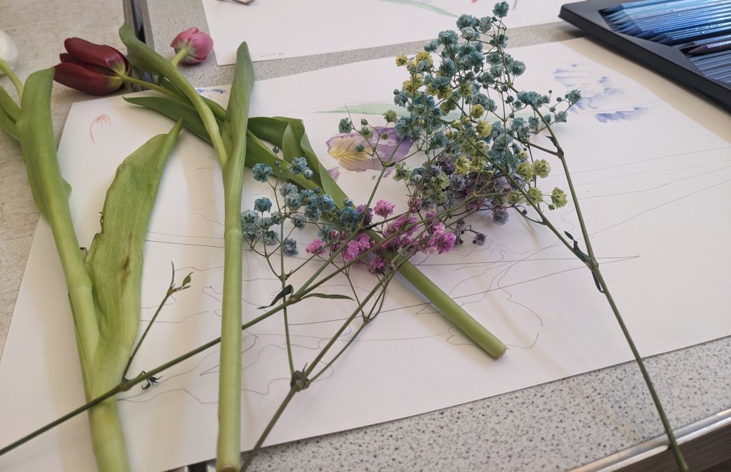 Different sets of flowers used in the workshop laid on finished artwork.