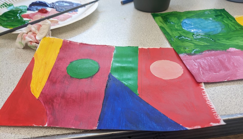 photo of three line landscape that has a Sun and Moon. Sun is Green and Moon is coral both are on red blocks there is a green rectangle in the middle and a dark blue triangle at the bottom.