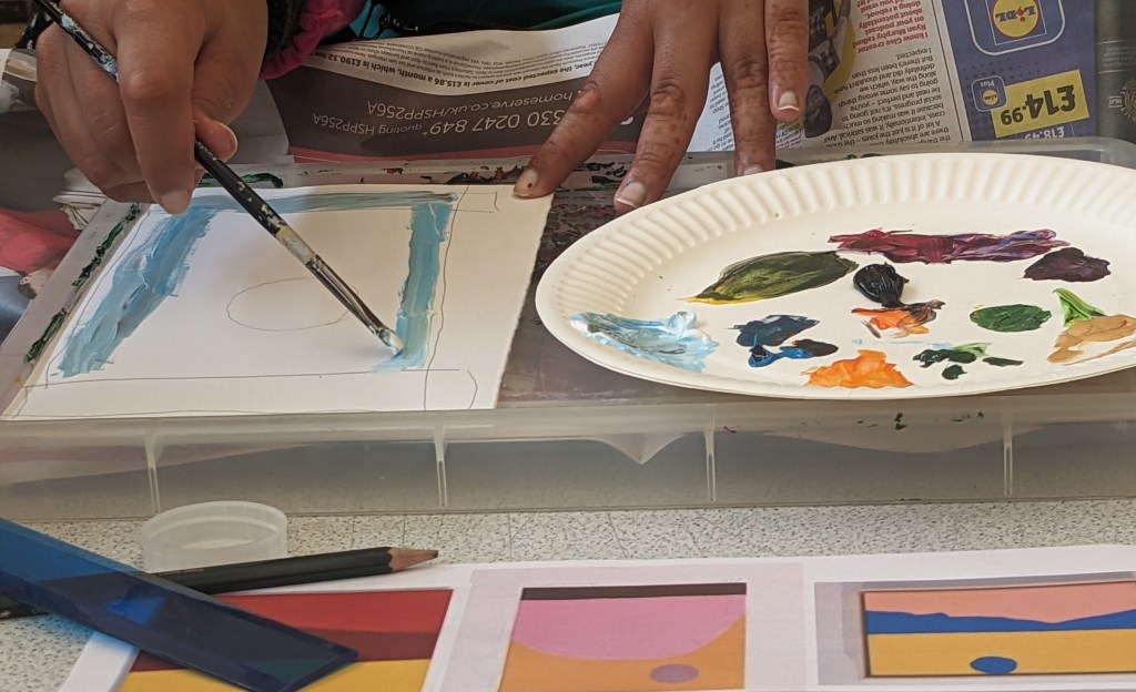 Picture of someone painting their three line landscape. They are using a sky blue colour.