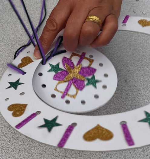 Image of creation of Dreamcatcher. It has a pink and yellow sparkly flowe in the middle and green stars, yellow hearts around it.