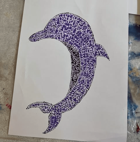 Artwork inspired by Aboriginal art. it is a dot painted Dolphin using shades of purple and blue. 