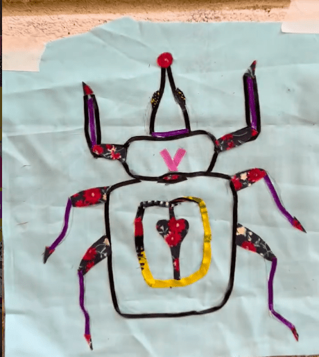 photo of Beetle, it is has a red floral pattern throughout. Yellow is in a quater bottom of the middle of it with the red floral pattern returning 