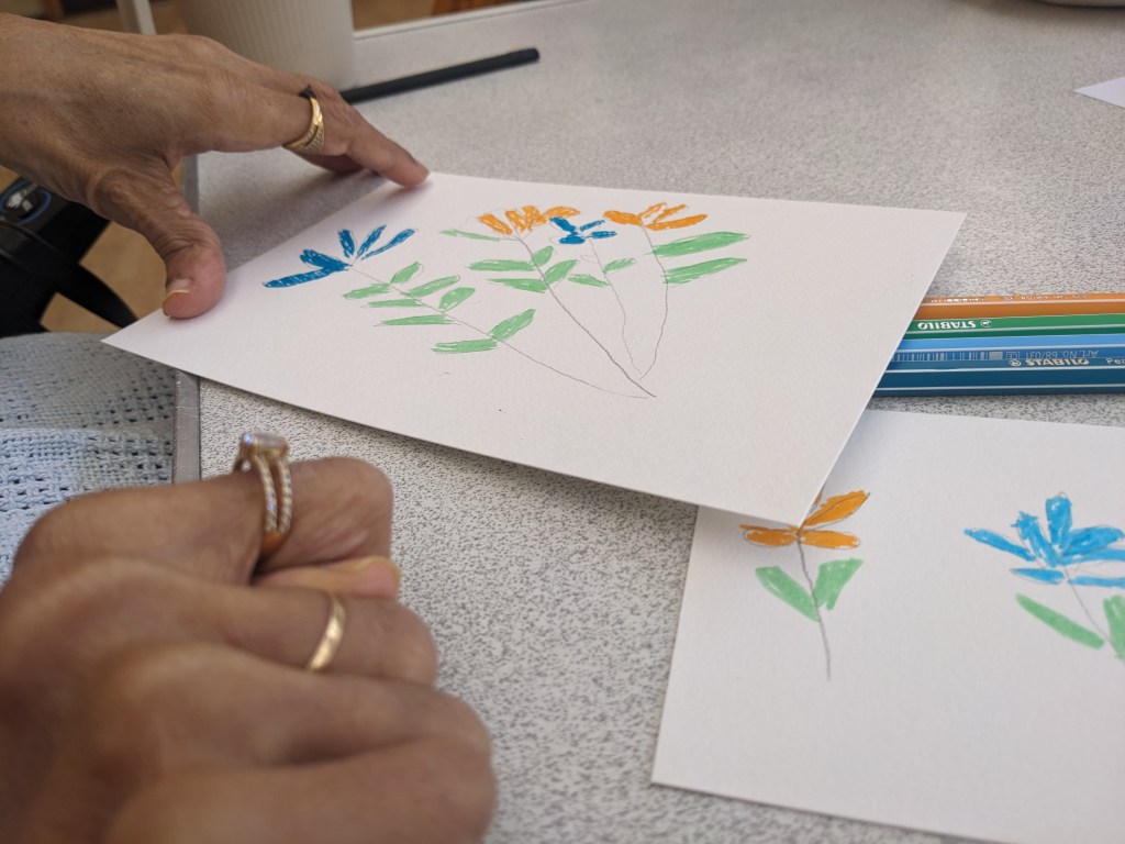 Photo of two sets of Blue and Orange flowers with green stems and leaves. Created using marker and pencil. 
