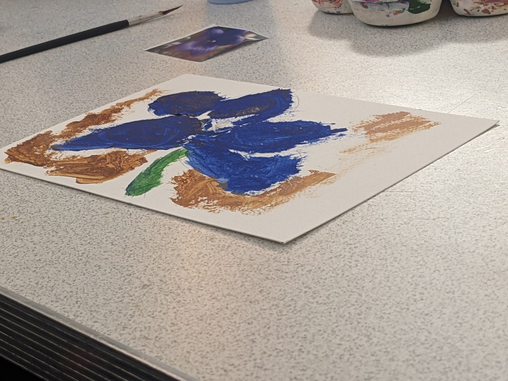 Picture of artwork. It has a blue flower with 5 petals, a yellow centre and green stem surrounded by brown dabs of colour. 