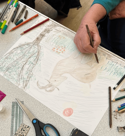 Drawing of a Goat in a forest surrounded by grass and bushes of flowers.